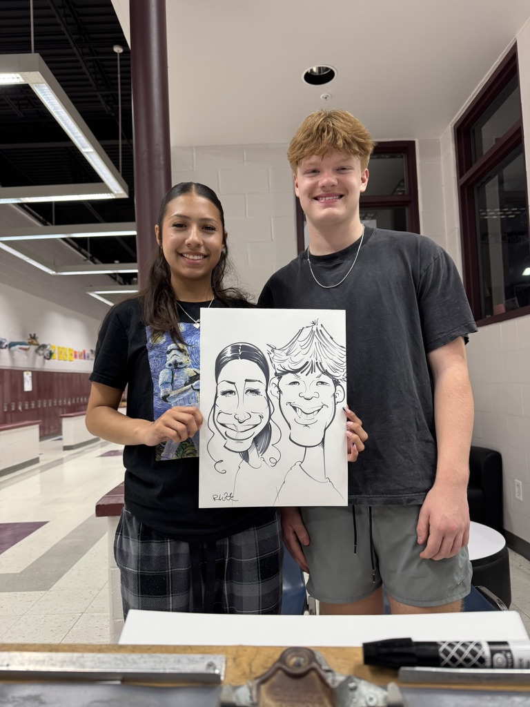 Two students hold a live black-and-white caricature in a school hallway