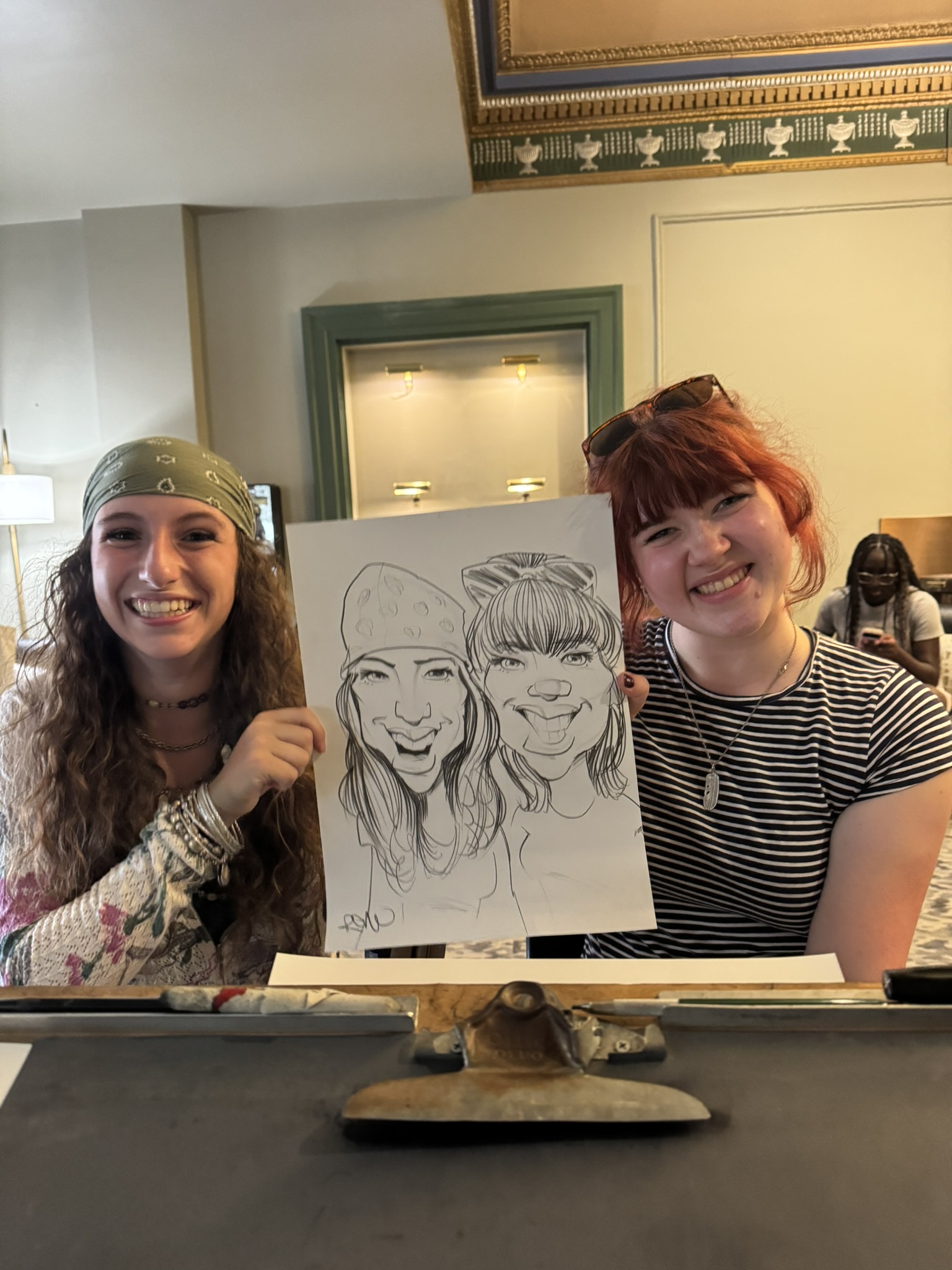 Two guests smile beside a live caricature drawn on a large sheet